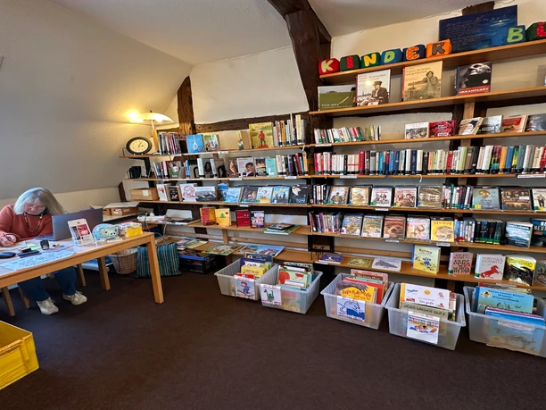 A view of the library's well-stocked children's book section, with full shelves and boxes of books.