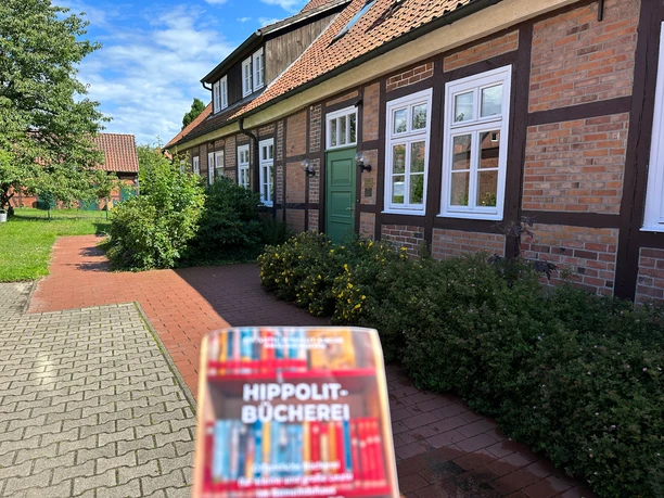 Hippolit Bücherei Broschüre vor dem Eingang des Fachwerkgebäudes der Hippolit-Bücherei.