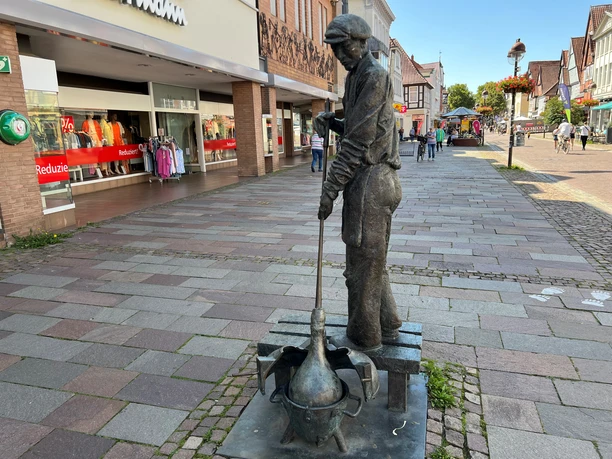 Eine Statue eines Glasbläsers auf einem Marktplatz, der konzentriert Glas formt.