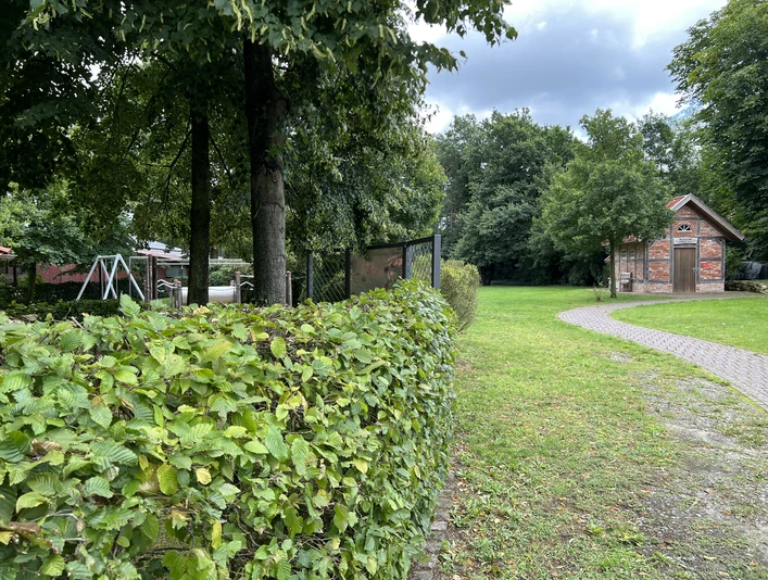 Ein einladender Mehrgenerationenplatz mit gepflegtem Rasen, ruhigen Wegen und grüner Vegetation.