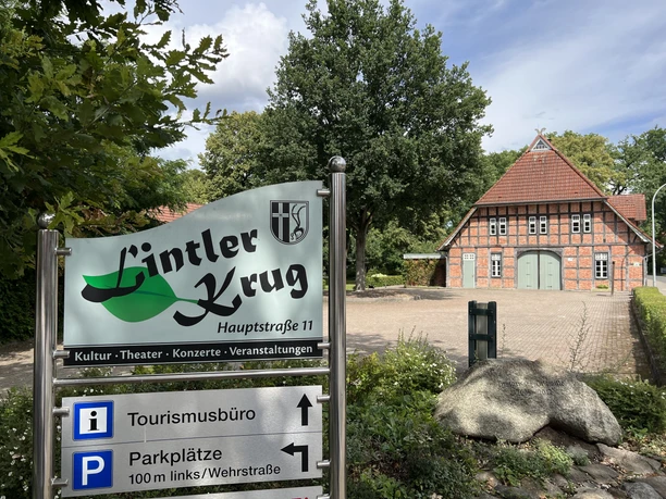 Lintler Krug Der Lintler Krug ist ein traditionelles Backsteingebäude mit begrüntem Vorplatz und großem Baum.