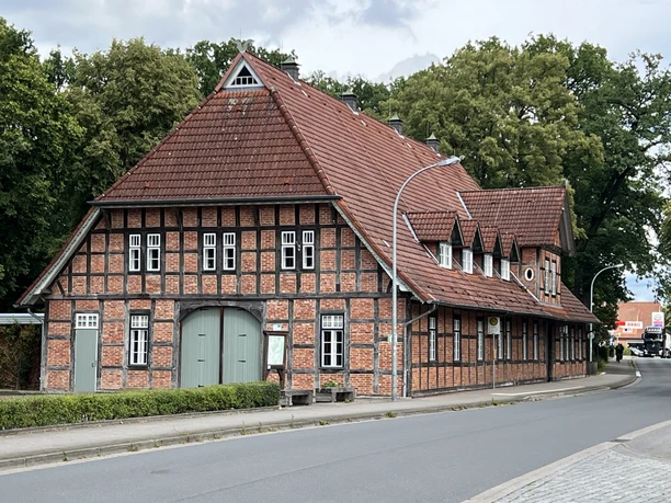 The half-timbered Lintler Krug building with its red tiled roof is located on a quiet street in a green setting.