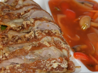 knusprige Ente bei Gnoc Thao. Knusprige Entenscheiben auf gebratenen Nudeln, serviert mit einer Seite würziger Gemüsesauce.