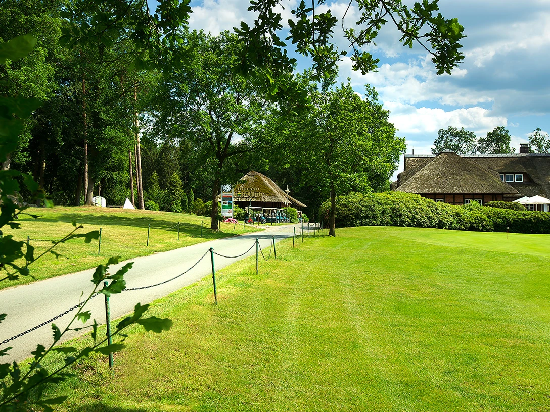 The path leads to a thatched clubhouse in the Artland Golf Club, surrounded by green countryside.
