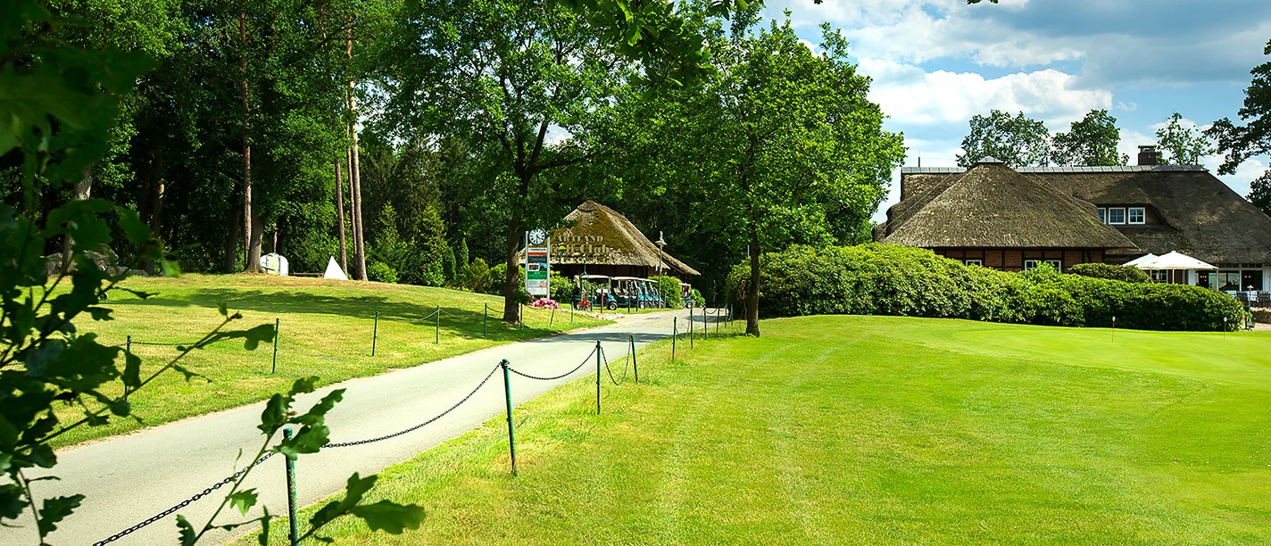 artland-golfclub The path leads to a thatched clubhouse in the Artland Golf Club, surrounded by green countryside.