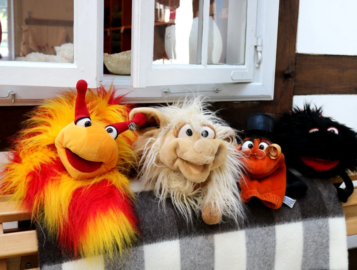 Tuchmacher Museum Bramsche im Osnabrücker Land Vier bunte Stofftiere sitzen lächelnd auf einer Holzbank vor einem Fachwerkhausfenster.Four colorful stuffed animals sit smiling on a wooden bench in front of a half-timbered house window.Fire farverige tøjdyr sidder smilende på en træbænk foran et vindue i et bindingsværkshus.Vier kleurrijke knuffeldieren zitten glimlachend op een houten bankje voor het raam van een vakwerkhuis.