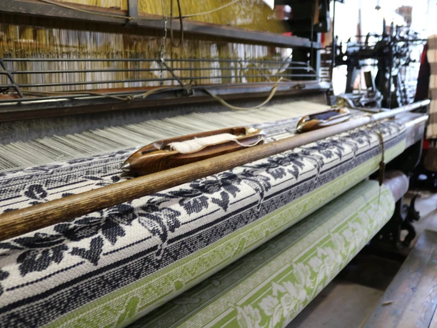 Tuchmacher Museum Bramsche im Osnabrücker Land Historical loom with colorfully woven fabric in a workshop.