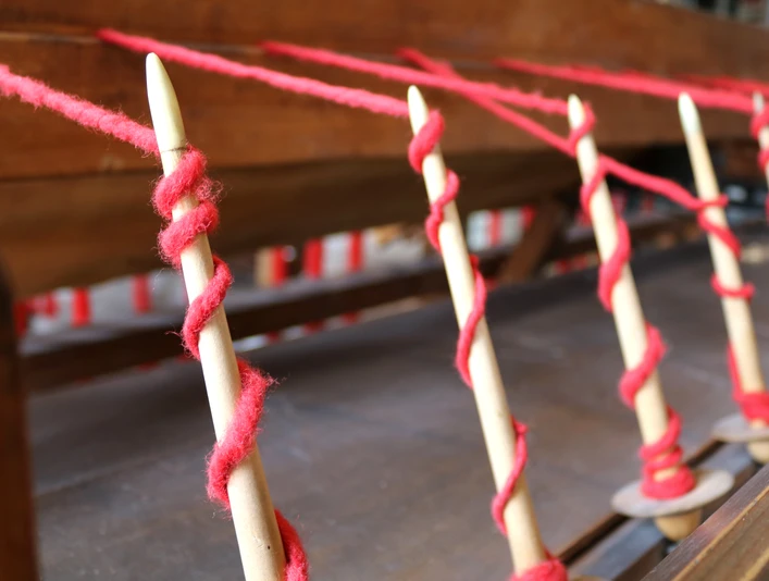 Tuchmacher Museum Bramsche im Osnabrücker Land Spindeln mit rotem Faden, bereit zur Verarbeitung in einer traditionellen Webmaschine.Spindles with red thread, ready for processing in a traditional weaving machine.Spindler med rød tråd, klar til behandling i en traditionel vævemaskine.Spindels met rode draad, klaar voor verwerking in een traditionele weefmachine.