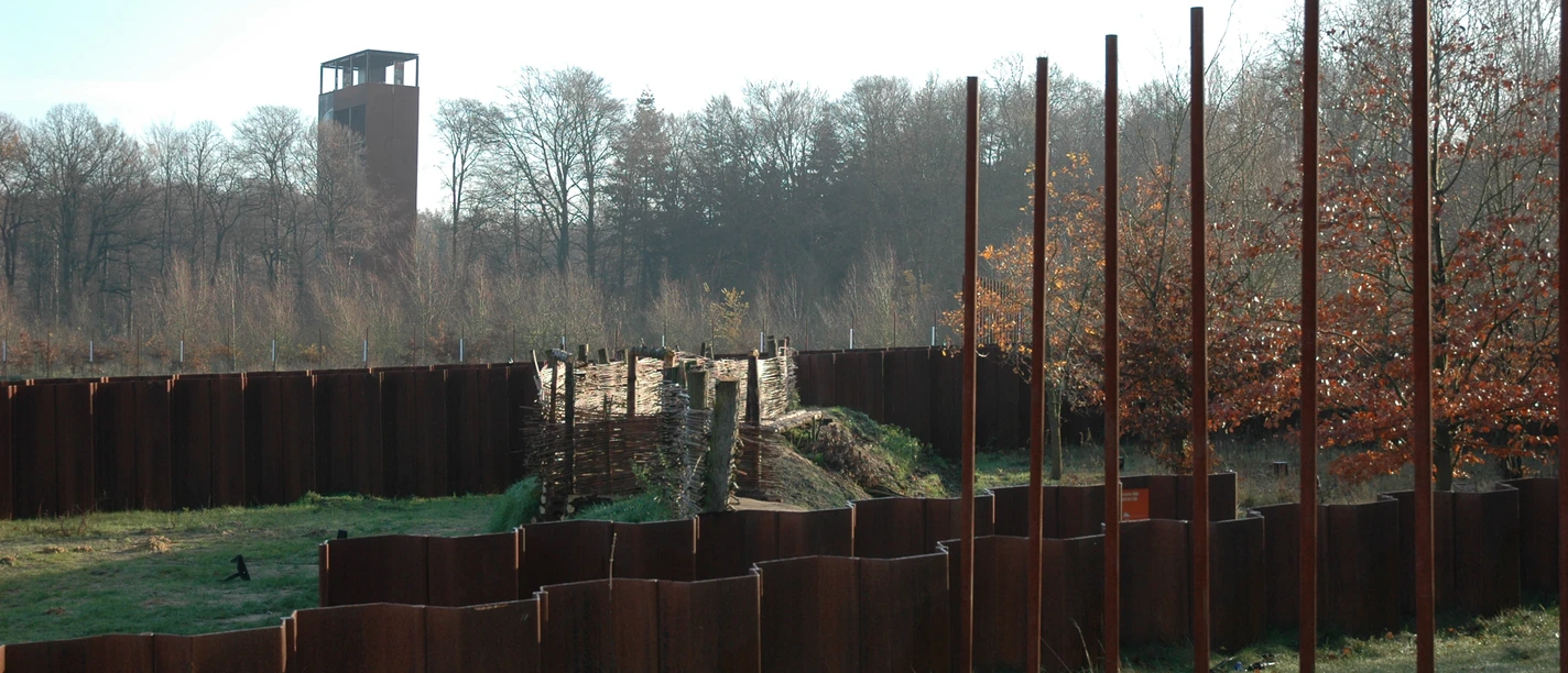 Varusschlacht im Osnabrücker Land - Museum und Park Kalkriese Historische hölzerne und metallene Grenzanlage mit Turm im Hintergrund, umgeben von Bäumen.
