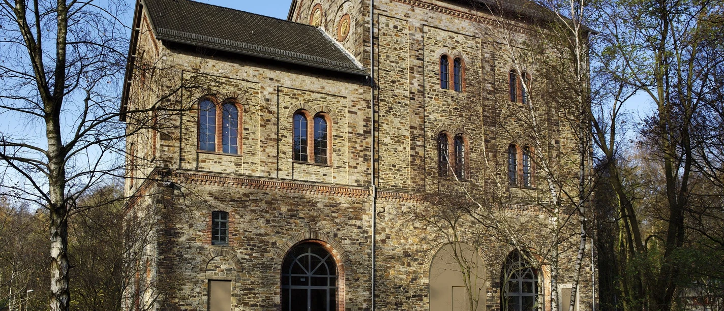 Das Museum Industriekultur in Osnabrück Brick building of the Museum of Industrial Culture in Osnabrück with arches and windows, surrounded by trees.