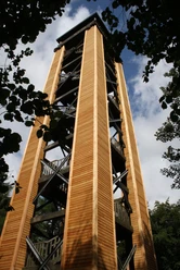 Klimaturm in Melle im Osnabrücker Land Holzturm mit mehreren Aussichtsplattformen, umgeben von Bäumen, ragt in den blauen Himmel.