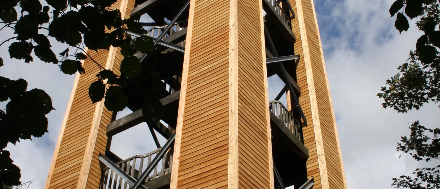 Klimaturm in Melle im Osnabrücker Land Holzturm mit mehreren Aussichtsplattformen, umgeben von Bäumen, ragt in den blauen Himmel.