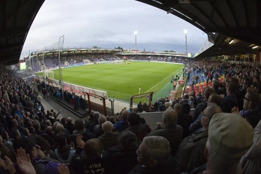 Das VfL-Stadion an der Bremer Brücke Stadion an der Bremer Brücke gefüllt mit jubelnden Fans in der Abenddämmerung während eines Spiels.