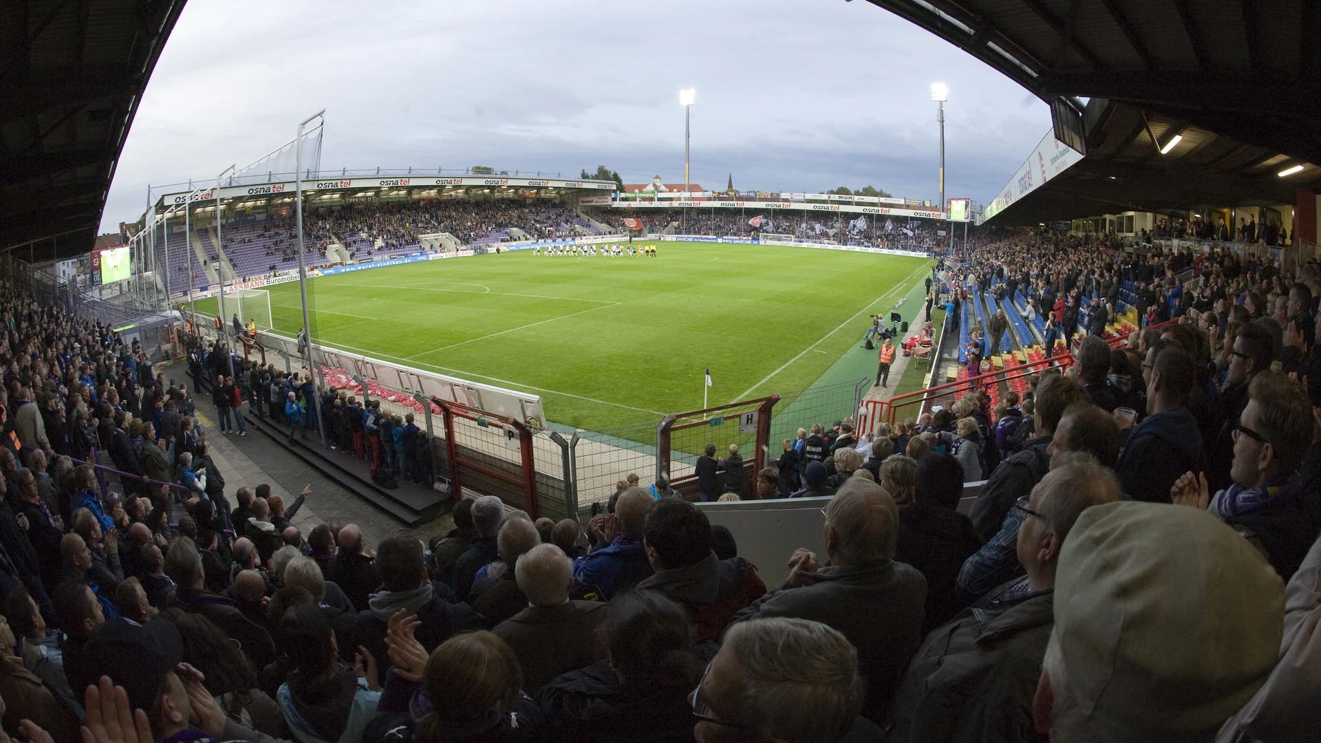 Stadium at Bremer Brücke filled with cheering fans at dusk during a match.