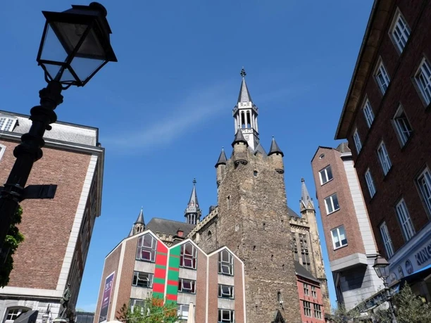 Granusturm Der viereckige Granusturm steht in der Mitte historischer Gebäude vor blauem Himmel.