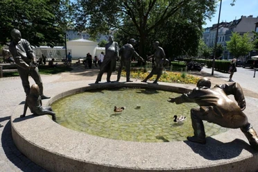 Bronzefiguren am Brunnenrand, die Geiz, Gönnerhaftigkeit, Bettelei und Gier darstellen.