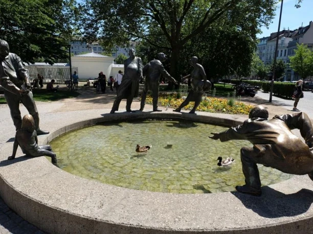 Bronzefiguren am Brunnenrand, die Geiz, Gönnerhaftigkeit, Bettelei und Gier darstellen.