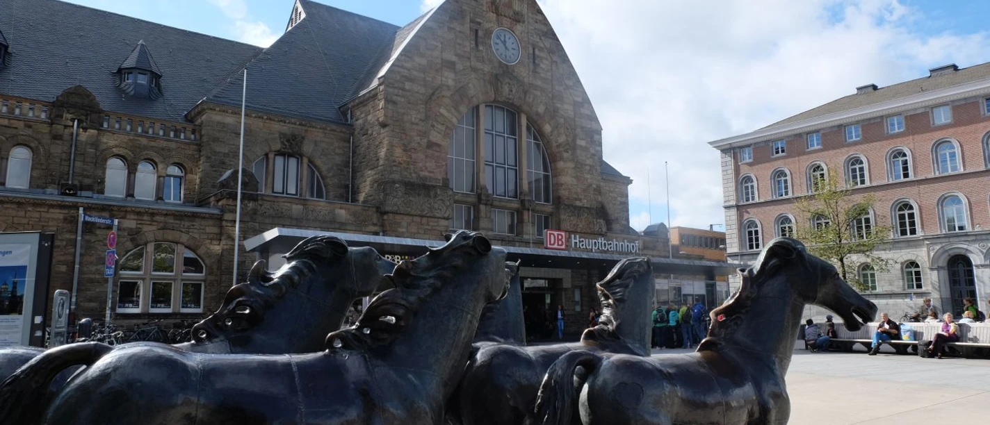 Vor dem historischen Gebäude des Aachener Hauptbahnhofes stehen vier Pferde aus Bronze auf dem Vorplatz.