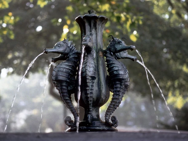 Seepferdchenbrunnen Burtscheid Ein symmetrischer Brunnen mit Seepferdchen aus Bronze, die Wasser speien.