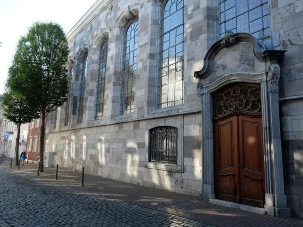 Fassade mit hohen Buntglasfenstern und einer kunstvollen Holztür.