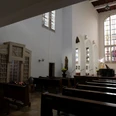 Innenansicht der Klosterkirche mit schlichter Einrichtung, Kirchenbänken und bunten Glasfenstern.