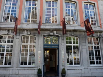 Die Fassade des Couven Museums mit ihren klassisch weißen Sprossenfenstern und roten Backsteinakzenten sowie der blauen Eingangstür mit goldenen Verzierungen..