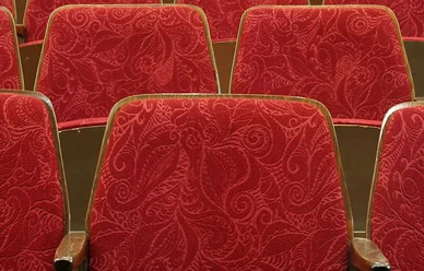 Theatersitze mit Holzrahmen und rotem Samtbezug.