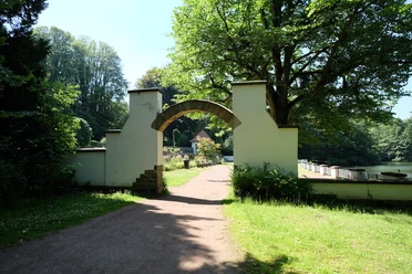 Kaiser-Friedrich-Park Ein Torbogen inmitten von Bäumen führt zu einem ruhigen Spazierweg.