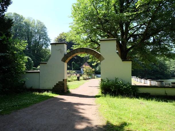 Kaiser-Friedrich-Park Ein Torbogen inmitten von Bäumen führt zu einem ruhigen Spazierweg.
