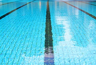 Boden eines mit Wasser gefüllten Schwimmbeckens mit schwarzen Bahnstreifen.