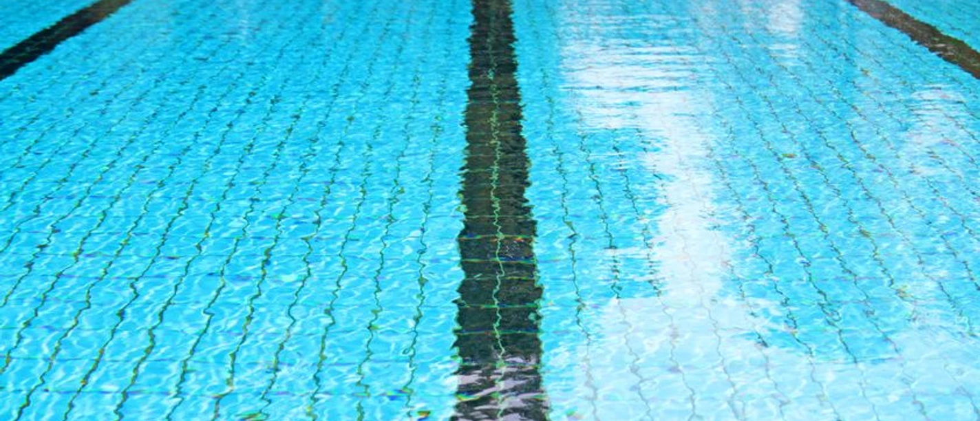Boden eines mit Wasser gefüllten Schwimmbeckens mit schwarzen Bahnstreifen.