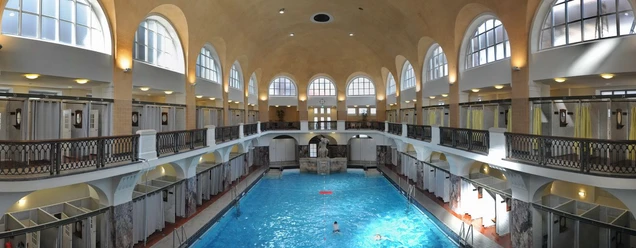Elisabethhalle Historisches Hallenbad mit hohem Gewölbe, Arkadenfenstern und zentralem Schwimmbecken.