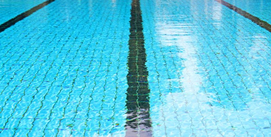 Schwimmbad (c) kara fotolia Boden eines mit Wasser gefüllten Schwimmbeckens, auf dem schwarze Bahnstreifen sind.