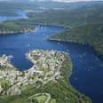 Rursee Panoramaansicht des sich schlängelnden Rursees mit grünen Hügeln und Segelbooten unter blauem Himmel.