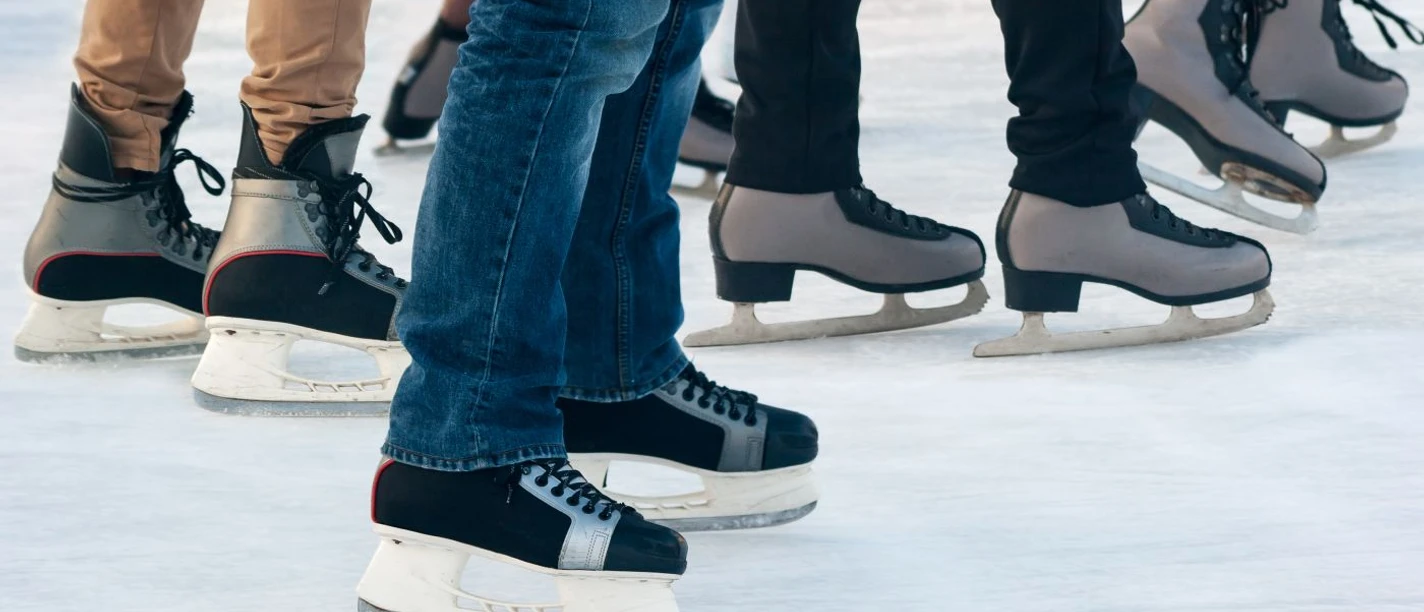 Mehrere Personen in verschiedenen Schlittschuhen gleiten auf Eis.