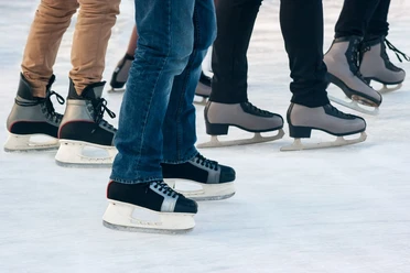 100,5 Arena - Eissporthalle Mehrere Personen in verschiedenen Schlittschuhen gleiten auf Eis.