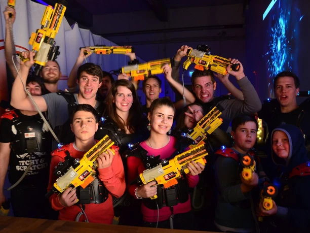 Black LaserTag Aachen Eine Gruppe junger Menschen posiert mit Begeisterung beim LaserTag, ausgestattet mit gelben Laserpistolen.