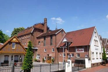 Edelkornbrennerei Jos. Rosche Edelkornbrennerei mit rotem Ziegeldach, Schornstein und Innenhof bei blauem Himmel in Haselünne.