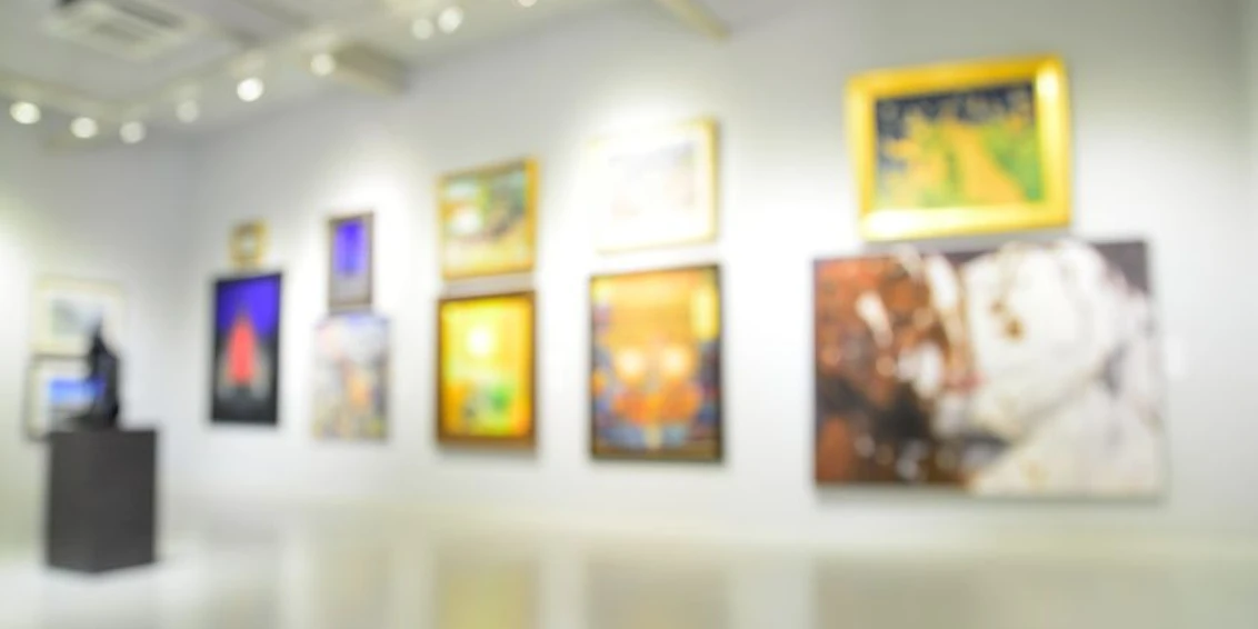 Atelierhaus Aachen Blau und rot gemusterte Wände mit unscharfen Gemälden in unterschiedlicher Größe.