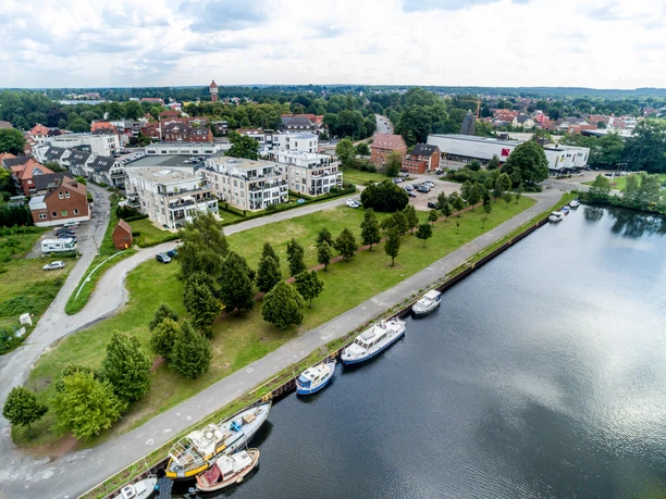 Alter Hafen Lingen Boote liegen am Ufer des Alten Hafens in Lingen, dahinter moderne Wohnhäuser und Grünflächen