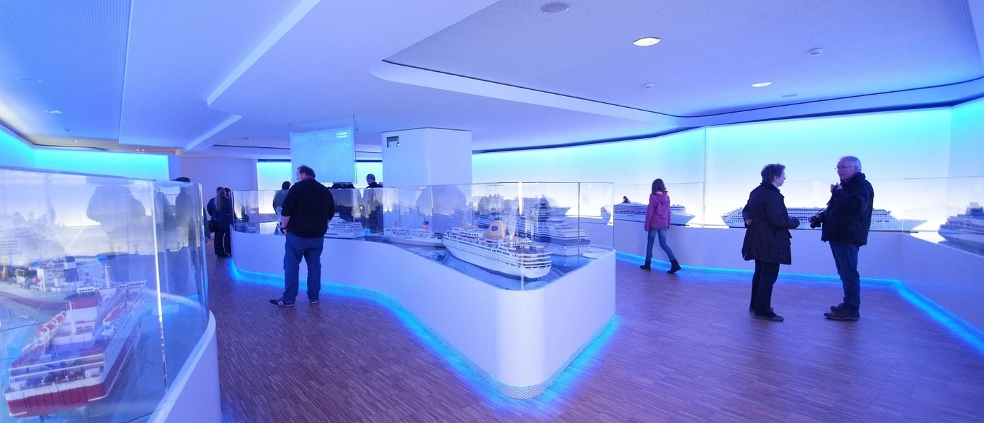 Besucherzentrum Meyer Werft Innenraum des Besucherzentrums mit beleuchteten Schiffmodellen und Gästen auf hellem Holzfußboden