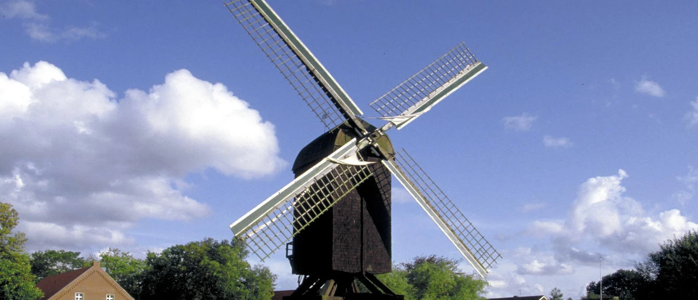 Bockwindmühle Papenburg Historische Bockwindmühle in Papenburg mit weißen Flügeln vor blauem Himmel und grüner Wiese.