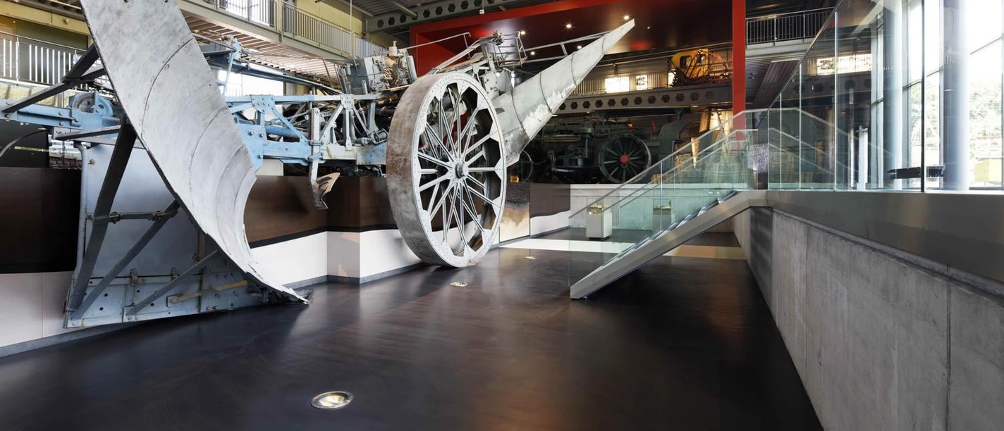 Emsland Moormuseum Großes historisches Moorfahrzeug mit Metallrädern in moderner Museumshalle mit Glas und Stahl.