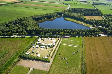 Erikasee mit Zeltplatz Luftaufnahme eines Sees im Grünen mit angrenzendem Zeltplatz, Feldern und umgebendem Wald.