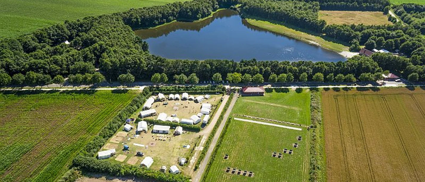Erikasee mit Zeltplatz Luftaufnahme eines Sees im Grünen mit angrenzendem Zeltplatz, Feldern und umgebendem Wald.