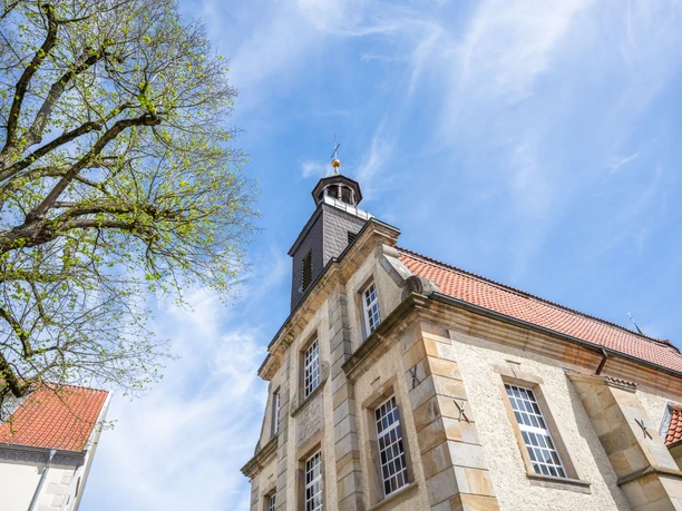 Evangelisch-lutherische Kreuzkirche Fassade der Kreuzkirche in Lingen mit rotem Ziegeldach und Turm vor blauem Himmel.