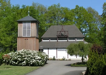 Evangelisch-lutherische Pauluskirche Evangelisch-lutherische Pauluskirche mit freistehendem Holzturm, umgeben von Grün und Blumen.