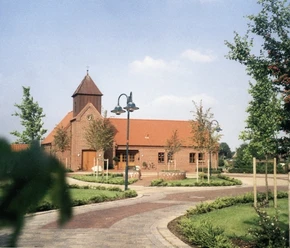 Martin-Luther-Kirchenzentrum Backsteinkirche mit rotem Ziegeldach, kleinem Turm und gepflegtem Vorplatz mit Bäumen und Wegen.