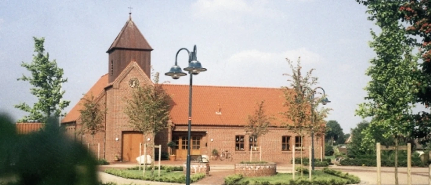Martin-Luther-Kirchenzentrum Backsteinkirche mit rotem Ziegeldach, kleinem Turm und gepflegtem Vorplatz mit Bäumen und Wegen.