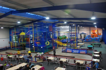 Familien-Hallenspielplatz Sternenland Bunte Kletteranlage und Hüpfburgen in großer Halle mit Spielbereich und Sitzplätzen für Familien